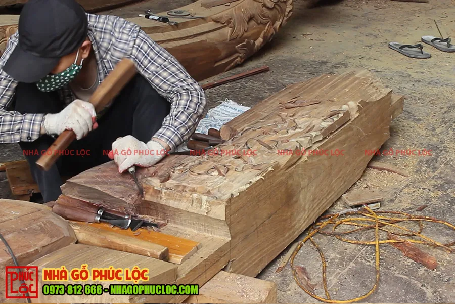 Hình ảnh người thợ chạm đang đục các hoa văn của nhà gỗ