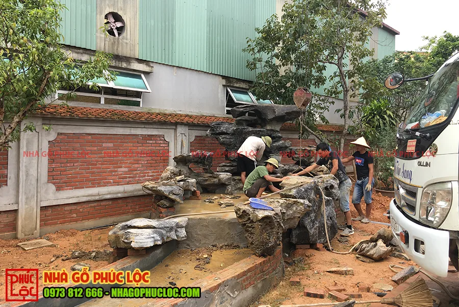 Đài dẫn nước cạnh bể cá của nhà gỗ sân vườn
