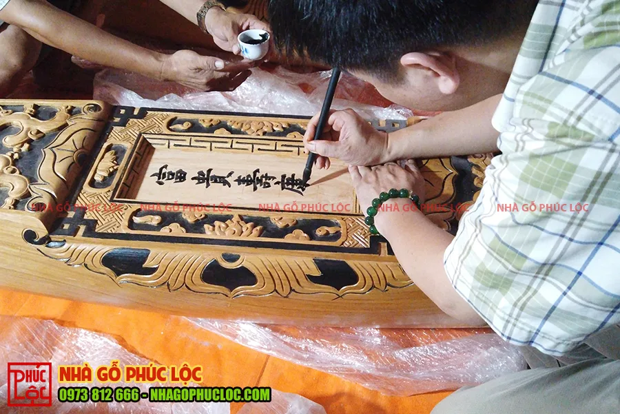 Thầy viết chữ trên câu đầu nhà gỗ